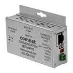 Ein Netzwerkgerät von ComNet mit Anschlüssen und Beschriftungen, montierbar an einer flachen Oberfläche.