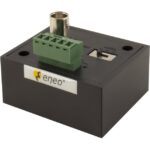 Ein rechteckiges, schwarzes Gerät mit einer grünen Anschlussklemme und einem Koaxialanschluss. Es trägt das Logo "eneo".