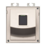 Ein rechteckiger Wandschalter mit einem zentral platzierten schwarzen Taster und einer metallischen Umrandung, befestigt mit vier Schrauben an den Ecken.