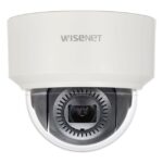 Eine weiße Überwachungskamera mit der Aufschrift "WISENET", die ein schwarzes Kameraobjektiv in einer durchsichtigen Kuppel zeigt.