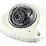 Eine weiße Kuppel-Sicherheitskamera mit transparentem Gehäuse.