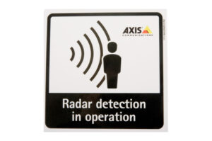 Bild mit einem Schild, das eine Figur neben Radarsignalen zeigt und die Aufschrift „Radar detection in operation“ trägt; Logo von AXIS COMMUNICATIONS.