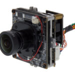 Eine elektronische Kameraplatine mit Objektiv und mehreren Kabelverbindungen.