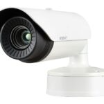 Eine weiße Überwachungskamera auf einem Sockel, frontal abgebildet.