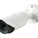 Eine weiße Überwachungskamera mit dem Schriftzug "Wisenet" an einer Wandhalterung.