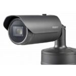 Überwachungskamera in einem schwarzen Gehäuse auf einer Halterung montiert.