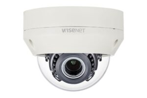 Eine weiße Überwachungskamera von Wisenet in einer kuppelförmigen Ausführung mit sichtbarem Kameraobjektiv im Inneren.