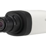 Kompakte Überwachungskamera mit Objektiv und schwarz-weißem Gehäuse, auf dem Hanwha-Logo zu sehen ist.