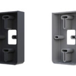 Zwei rechteckige Kunststoffgehäuse in dunklem und hellem Grau nebeneinander, mit mehreren Befestigungspunkten und einer Öffnung in der Mitte.