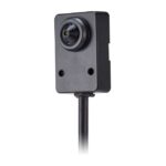 Eine kleine, schwarze Überwachungskamera mit rechteckigem Gehäuse und angeschlossenem Kabel.