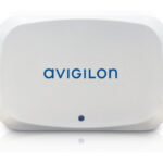 Ein weißes Gerät von Avigilon mit abgerundeten Ecken und einem kleinen blauen Punkt unten in der Mitte.