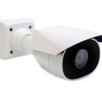 Eine weiße Überwachungskamera mit Wetterschutzgehäuse, montiert auf einer Wandhalterung.