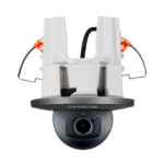 Eine Deckenüberwachungskamera mit schwarzem Objektiv, montiert auf einer weißen Halterung, mit sichtbaren Kabelverbindungen.