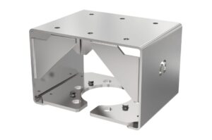 Ein silbernes, kubisches Metallbauteil mit mehreren kreisförmigen Bohrungen und abgekanteten Kanten.