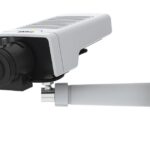 Eine Überwachungskamera in Weiß mit schwarzem Objektiv, montiert an einer Wandhalterung.