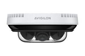 Eine weiße Überwachungskamera von Avigilon in einer Seitenansicht, erkennbar am transparenten Gehäuse, das die Kameraoptik zeigt.