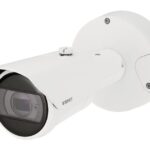 Eine weiße Überwachungskamera von Wisenet mit einem schützenden Gehäuse und einer Halterung zur Wandmontage.