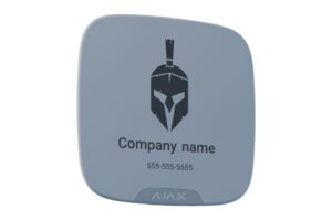 Ein graues, quadratisches Gerät mit abgerundeten Ecken, zeigt das Bild eines Helmes, den Text "Company name" und eine Telefonnummer. Unten ist das Logo "AJAX" sichtbar.