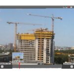 Ein unfertiges Hochhaus mit Baukränen im Hintergrund, angezeigt auf einer Zeitraffer-Videoanzeige.