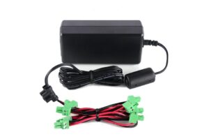 Ein schwarzes Netzteil mit Kabel, an dem sich ein Ferritkern befindet, und ein Satz von Kabeln mit grünen Steckverbindern, die rot und schwarz ummantelt sind.