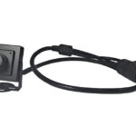 Eine kleine, quadratische Kamera mit Halterung und fest verbundenem langen Kabel, das in einen größeren Stecker mündet.