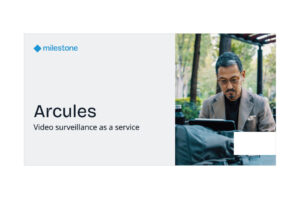 Ein Mann mit Brille und braunem Blazer sitzt im Freien und schaut konzentriert auf ein Tablet. Links im Bild steht "Arcules Video Surveillance as a Service" mit dem Markenlogo von Milestone.