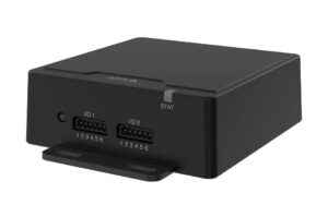 Schwarzes, rechteckiges Gerät mit zwei Anschlüssen auf der Vorderseite, die als 'I/O 1' und 'I/O 2' gekennzeichnet sind, sowie einer Statusanzeige mit der Aufschrift 'STAT'.