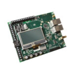 Eine grüne elektronische Leiterplatte mit einem kleinen Display, mehreren Anschlüssen und elektronischen Komponenten.