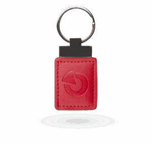Ein roter Schlüsselanhänger mit einer geprägten runden Grafik, befestigt an einem Metallring.