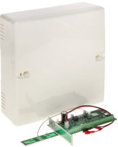 Ein weißes Kunststoffgehäuse neben einer grünen Leiterplatte mit elektronischen Bauteilen und Kabeln.