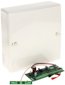 Weiße Kunststoffbox mit einer grünen Leiterplatte und elektrischen Komponenten davor, Kabel sind verbunden.