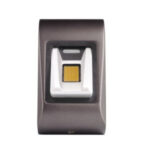 Ein biometrisches Fingerabdruck-Erkennungssystem mit einem matten, metallischen Gehäuse und einem goldfarbenen Sensor in der Mitte.