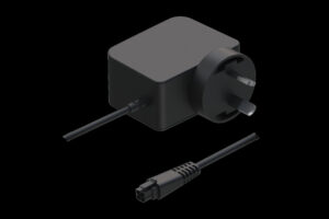 Ein schwarzes Netzteil mit einem dreipoligen britischen Stecker und einem abnehmbaren Stromkabel in einem minimalistischen Design.