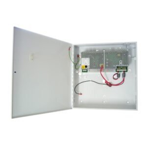 Geöffneter weißer Metallkoffer mit einem elektrischen Schaltnetzteil innen, verbunden mit roten und schwarzen Kabeln, sowie einer grünen Erdungskabelverbindung.