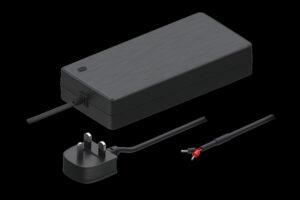 Ein großes schwarzes Netzteil mit einem Netzkabel und einem dreipoligen Steckdosenadapter sowie einem offenen Kabelende mit roten und schwarzen Drähten auf schwarzem Hintergrund.