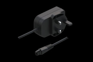 Netzadapter mit dreipoligem Stecker und Kabelendstück auf schwarzem Hintergrund.
