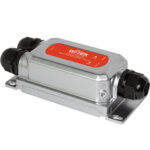 Ein rechteckiges, silbernes Gerät mit einer roten Beschriftung, das für den industriellen Einsatz geeignet ist, mit zwei schwarzen Kabelanschlüssen an den Enden.