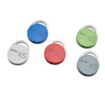 Fünf runde Schlüsselanhänger in verschiedenen Farben (blau, weiß, rot, grün, grau) mit der Aufschrift 'SALTO KS'.