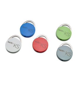 Fünf runde Schlüsselanhänger in verschiedenen Farben (blau, weiß, rot, grün, grau) mit der Aufschrift 'SALTO KS'.