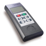 Schwarzes elektronisches Gerät mit einem kleinen Bildschirm und mehreren farbigen Tasten, darunter ein roter "C"-Knopf und ein grüner "OK"-Knopf.