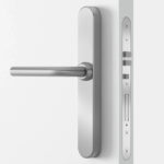 Türgriff aus Edelstahl auf einer weißen Tür, mit sichtbarem Schlosskasten und Schlüsselloch.