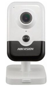 Eine weiße Überwachungskamera von Hikvision mit einem schwarzen Sockel und integrierter Linse, montiert auf einem weißen Standfuß.