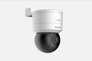 Eine Überwachungskamera von Hikvision in schwarz-weißer Farbgebung, montiert an einer Wandhalterung mit einer runden Kuppel für die Kamera."
