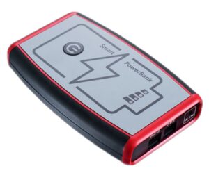 Ein tragbares Ladegerät mit rotem Rand und grauer Oberfläche, auf der ein Blitzsymbol und die Aufschrift 'Smart PowerBank' zu sehen sind. Es verfügt über Anschlüsse an einer Seite.