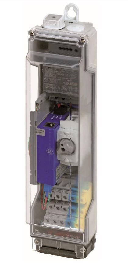 Ein transparenter Kunststoffkasten mit einem elektrischen Schaltschütz und Anschlüssen im Inneren, erkennbar durch ein violettes Bauteil und mehrere Kabel. An der Oberseite befindet sich ein Aufhängeloch für die Montage.