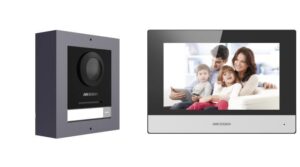 Eine Gegensprechanlage von Hikvision mit einer Kameraeinheit links und einer Monitoranzeige rechts, die ein Bild einer lächelnden Familie zeigt.