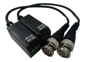 Zwei BNC-Stecker, die jeweils mit einem rechteckigen schwarzen Adaptergehäuse verbunden sind, das mit einem kurzen Kabel verbunden ist.