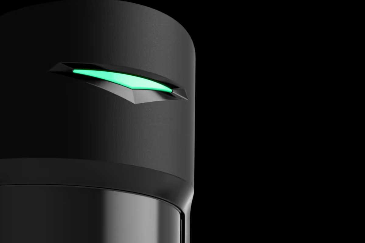 Teil eines schwarzen, zylinderförmigen Geräts mit einem leuchtenden, grünen Element an der Oberseite auf schwarzem Hintergrund.