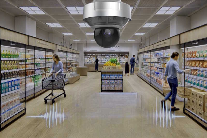 Ein Kameraüberwachungssystem in einem modernen Supermarkt mit wenigen Kunden, die in den Gängen einkaufen.