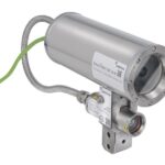 Zylindrische Industriekamera mit Metallgehäuse und Kabelanschlüssen, montiert auf einer kleinen Halterung.